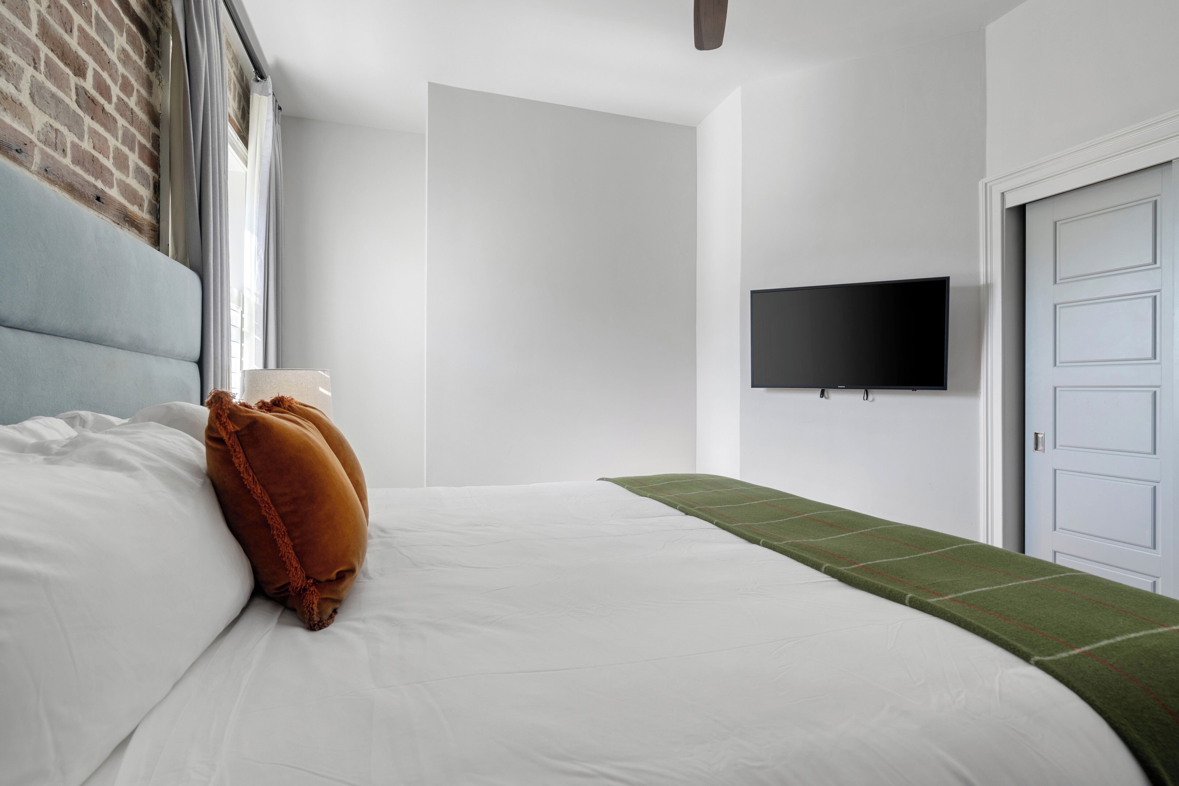 Una habitación de hotel con una cama, un televisor de pantalla plana en la pared y una puerta.