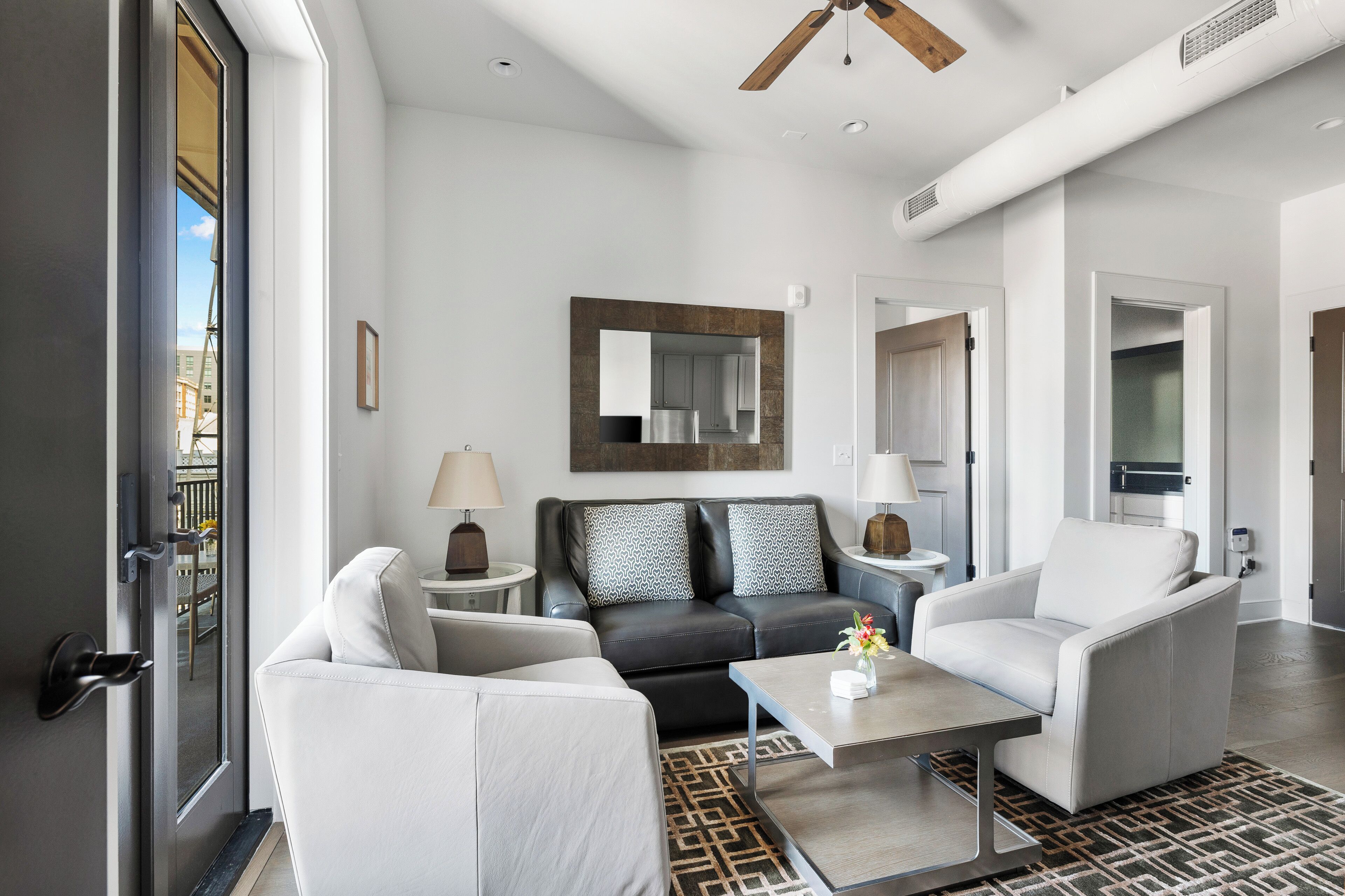 A modern living room with a sofa, armchairs, a coffee table, and a large mirror.