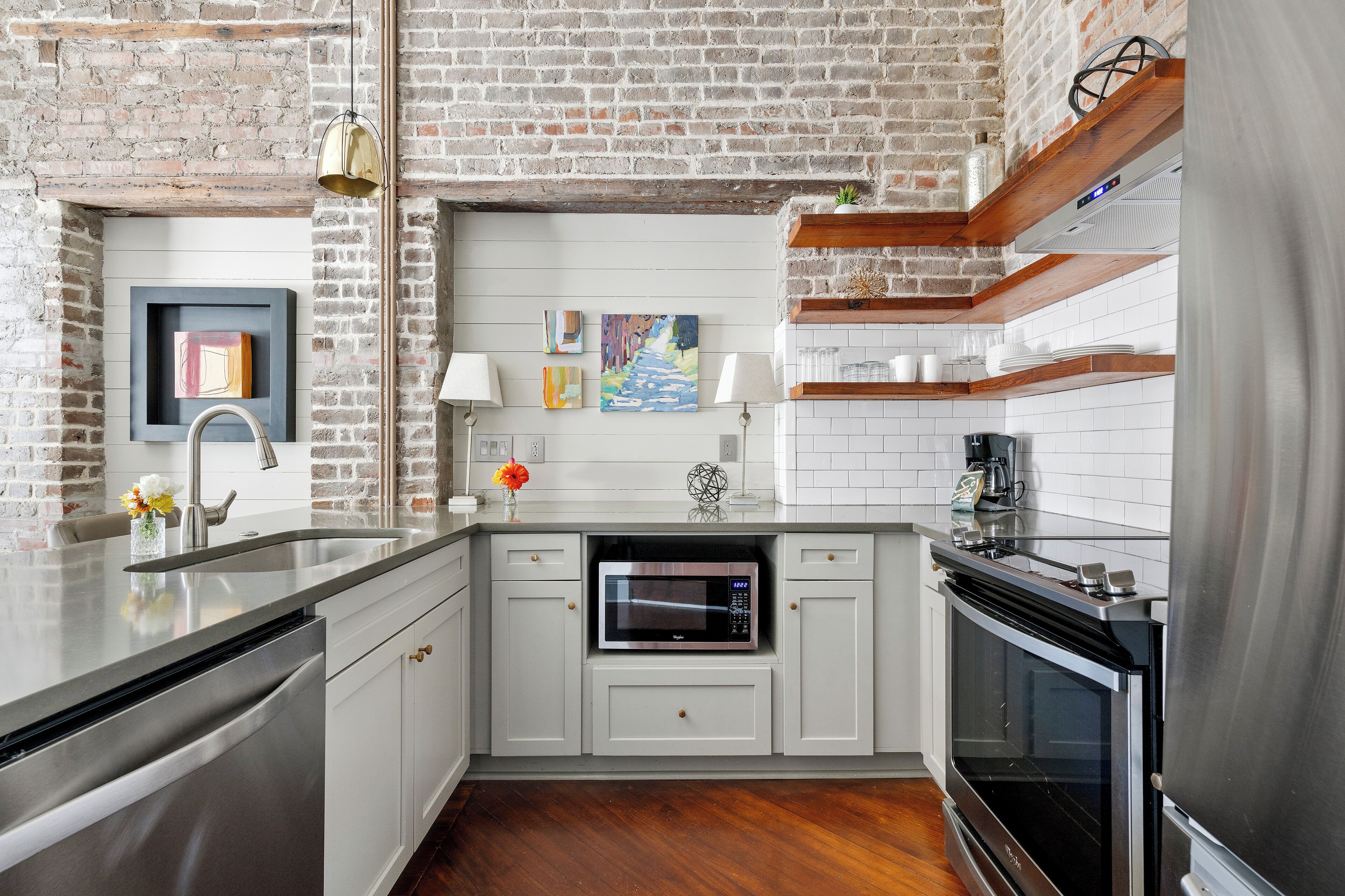 A kitchen with white cabinetry, a stainless steel refrigerator, a built-in microwave, and a wooden countertop.