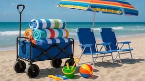 Een strandscène met een strandkar, twee strandstoelen, een kleurrijke streepjes parasol en een strandbal.