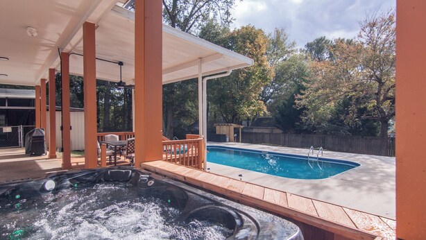 Ein Whirlpool mit einer Holzterrasse und einem Pool im Hintergrund.