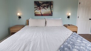 Ein Schlafzimmer mit einem Bett, zwei Nachttischen, einer Wandlampe und einer Tür.