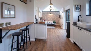 A kitchen with a wooden counter, stools, a radiator, and a brick wall.