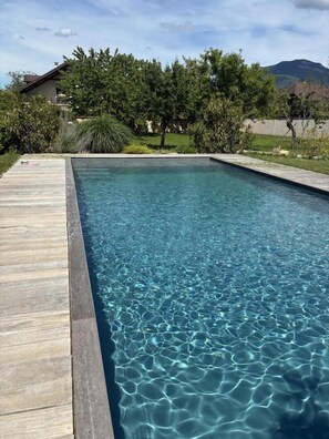 Ein rechteckiger Pool mit klarem Wasser, umgeben von einer Holzterrasse.