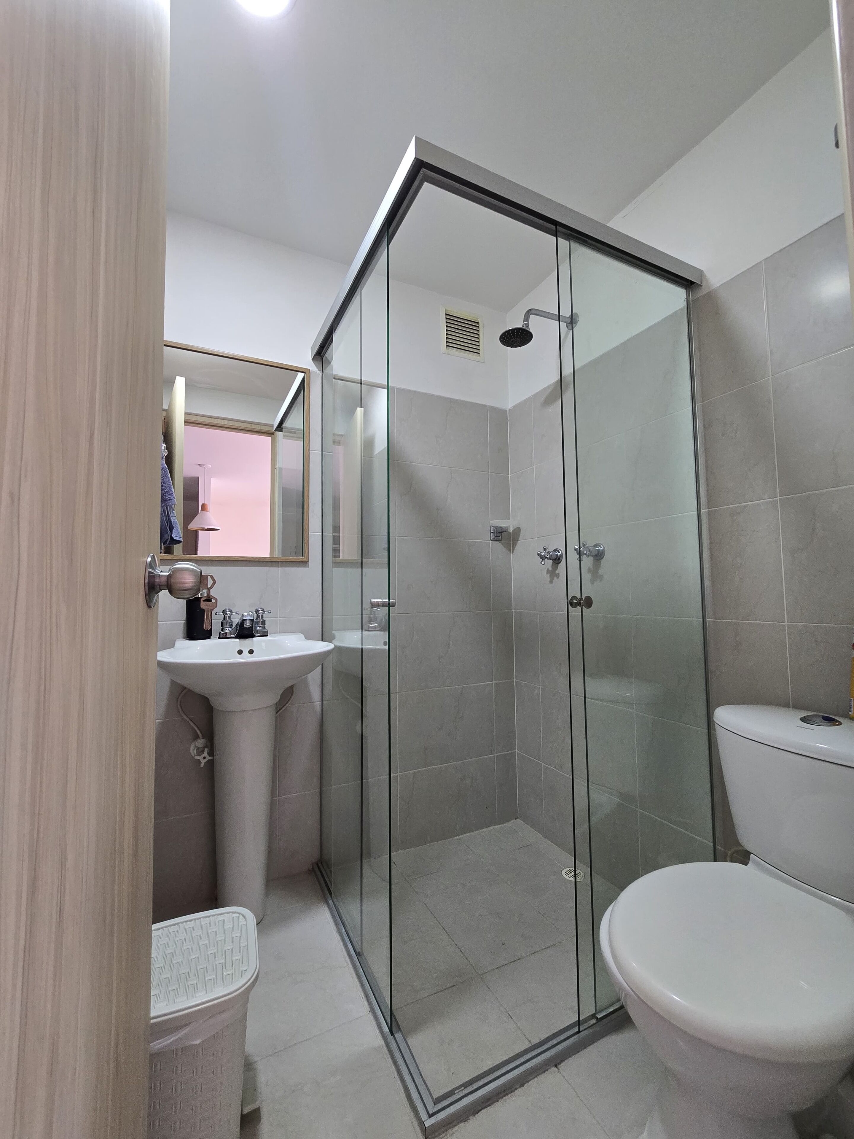 A bathroom with a glass-enclosed shower, a sink, and a toilet.