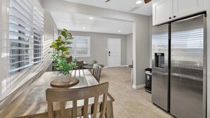 A kitchen with a stainless steel refrigerator, a dining table with chairs, and a ceiling fan. - 10 Min to Mission Beach & Sea World | Kids Playset (San Diego)