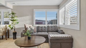 A modern living room with a sectional sofa, a round wooden coffee table, and a potted plant. - 10 Min to Mission Beach & Sea World | Kids Playset (San Diego)
