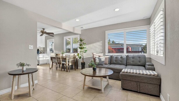 A spacious living area with a sofa, two coffee tables, a dining table with chairs, and a kitchen in the background. - 10 Min to Mission Beach & Sea World | Kids Playset (San Diego)