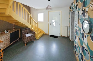 Eine Treppe, eine Tür, eine Wand mit Muster und ein Korbstuhl.