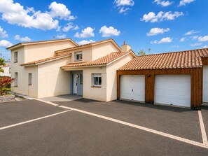 Un immeuble résidentiel de deux étages, doté d’un garage, d’une allée et surplombant un ciel bleu dégagé.