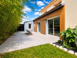 Une maison moderne dotée d’un patio, d’une table à manger et d’un jardin.