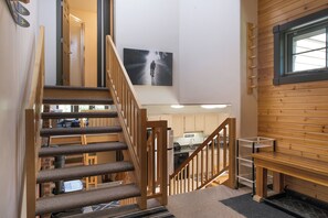 Eine Treppe führt zu einem Küchenbereich mit Holzwänden, einem großen Fenster und einem Schwarz-Weiß-Kunstwerk an der Wand.