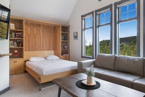 Ein Schlafzimmer mit Bett, einer Couch, einem Holztisch und einem Bücherregal.