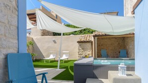 Eine Terrasse mit blauem Stuhl, einem Rattansofa, einem kleinen Tisch und einem Poolbereich mit Liegestühlen.