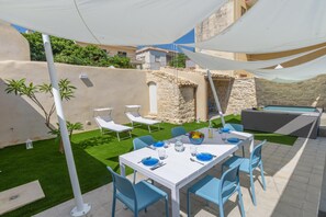 Eine Außenpatio mit Esstisch, Stühlen, einem Pool und einer Steinmauer.
