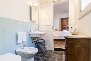 Ein Badezimmer mit Toilette, Bidet, Waschbecken, Spiegel und einem Holzschrank.