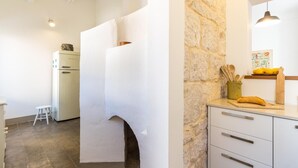 Eine Küche mit Steinwand, einem weißen Kühlschrank und einem Holzschneidebrett.