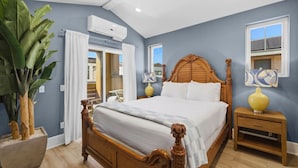 Ein Schlafzimmer mit einem hölzernen Bett, einem Nachttisch, einer Topfpflanze und einem Fenster.