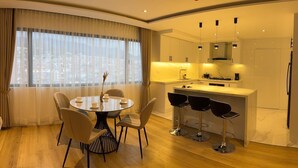 Ein modernes Hotelzimmer mit Essbereich, einer Küche und Blick auf die Stadt.