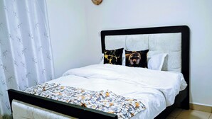 Ein Bett mit Kopfteil, Nachttisch und Vorhang.