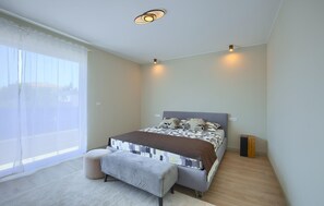 Une chambre à coucher avec un lit, un banc, une table de chevet et une fenêtre.
