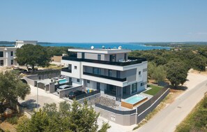 Un immeuble moderne à plusieurs étages, doté d’une piscine sur le toit et offrant une vue sur la mer.