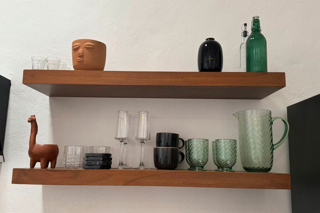 Two wooden shelves with various glassware and a ceramic llama figurine.