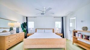 A bedroom with a wooden bed, bedside tables, a ceiling fan, a large window, and a bookshelf. - Waterfront 2BR with private screened pool (Rum Point)
