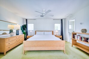 A bedroom with a wooden bed, bedside tables, a ceiling fan, a large window, and a bookshelf. - Waterfront 2BR with private screened pool (Rum Point)