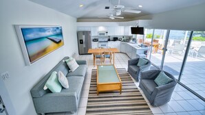 A modern living space with a sofa, a coffee table, and a television. - Waterfront 2BR with private screened pool (Rum Point)