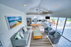 A modern living space with a sofa, a coffee table, and a television. - Waterfront 2BR with private screened pool (Rum Point)