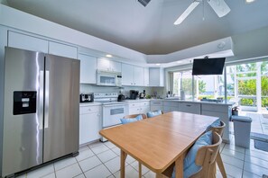 A modern kitchen with a stainless steel refrigerator, a microwave, and a dining area with a wooden table and chairs. - Waterfront 2BR with private screened pool (Rum Point)