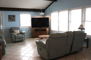 A living room with a sofa, a recliner, a TV on a stand, and a lamp. - Relaxing Coastal Retreat, Elevator, Dog Friendly (Emerald Isle)