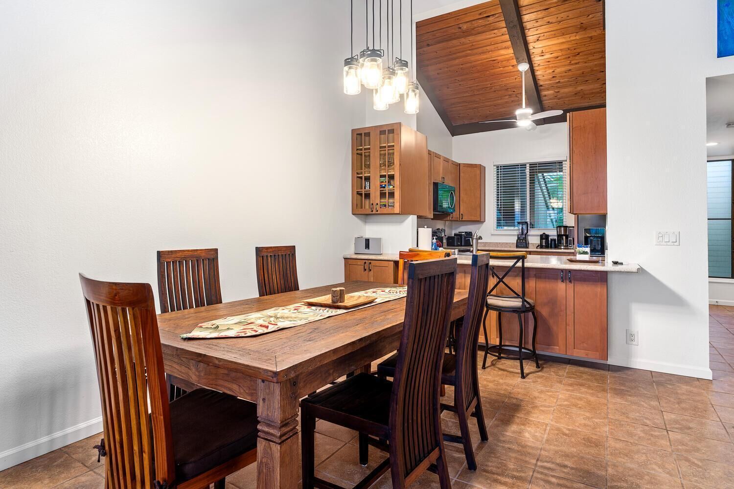A modern kitchen with wooden cabinets, a dining table with chairs, and a kitchen island.