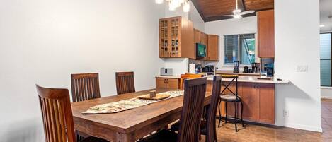 A modern kitchen with wooden cabinets, a dining table with chairs, and a kitchen island.