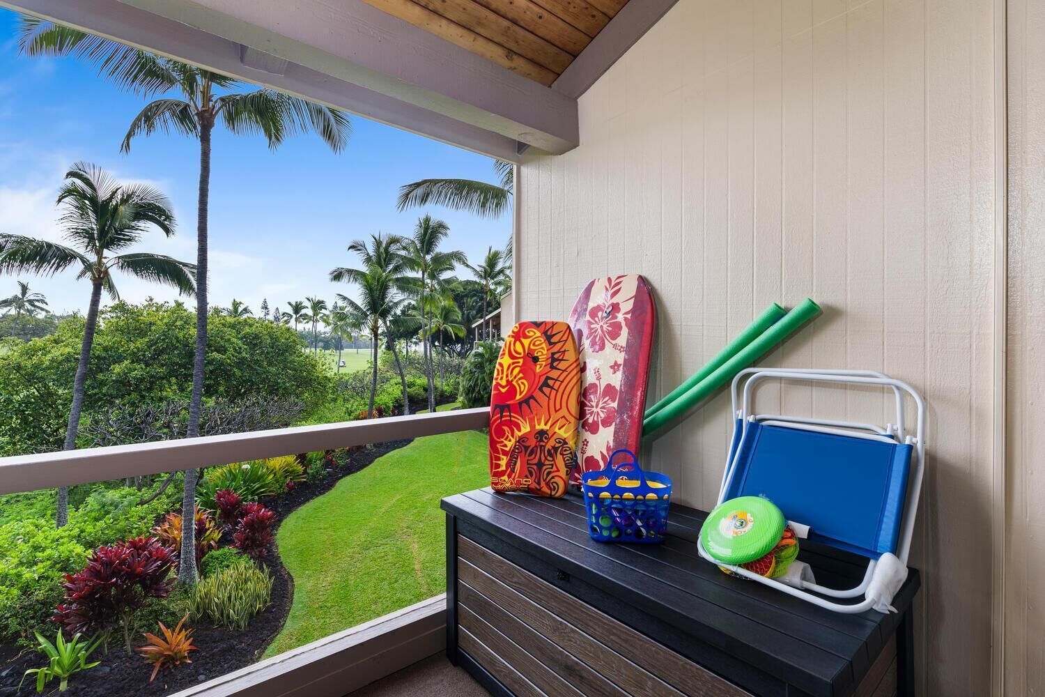 A balcony with surfboards, a beach ball, and a beach chair.