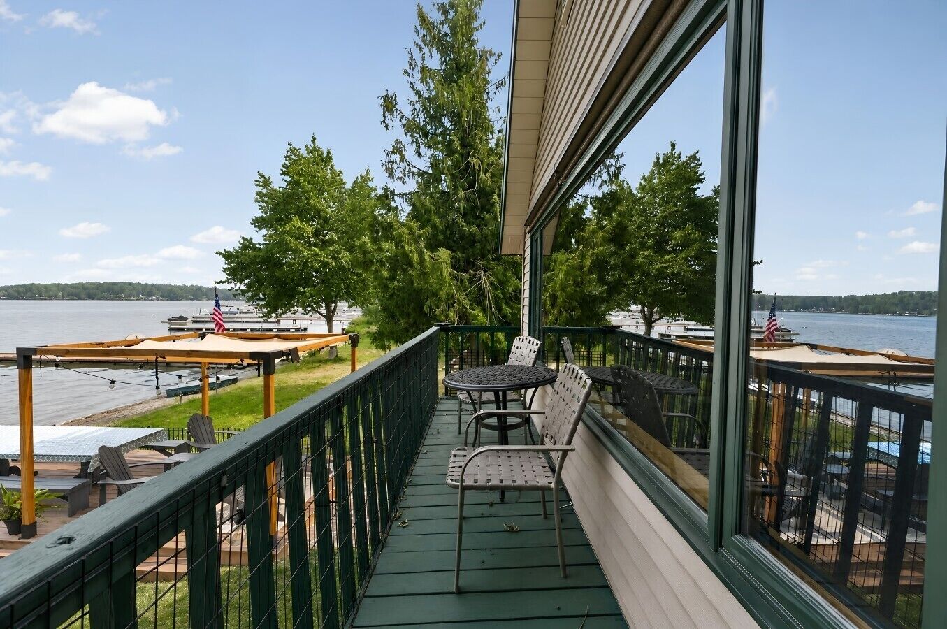 A balcony with outdoor seating, a view of the water, and American flags.