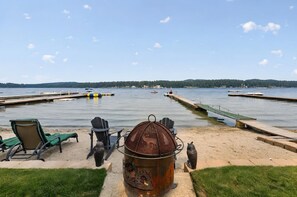 Une vue sur le lac avec un quai, des chaises et un barbecue.