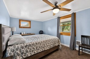 A bedroom with a bed, a ceiling fan, a window with curtains, a bedside table, and a chair. - Diamond Lake Retreat w Private Beach & Dock! (Newport)