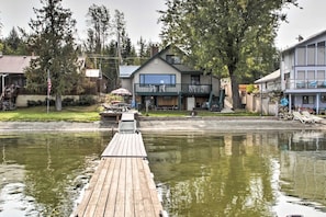 A waterfront property with a dock leading to a house with a balcony.