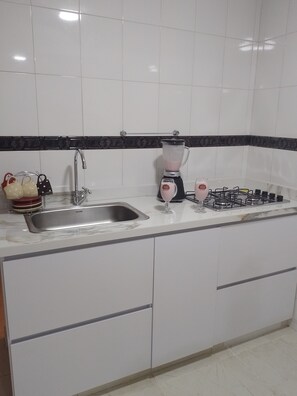 Una cocina con un lavamanos, una licuadora y una estufa a gas.