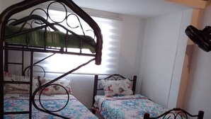 Una habitació amb dos llits superposats, una finestra amb persianes i un objecte penjant.