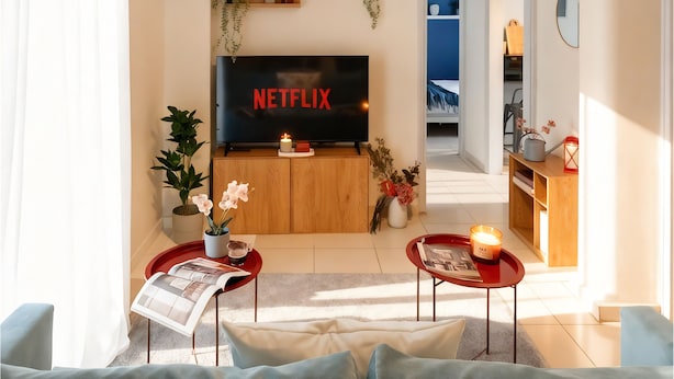 Olohuone, jossa on televisio, sohvapöytä, sohva ja kirjahylly.