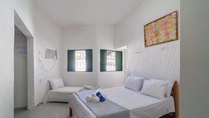 A small, clean room with two beds, a window with green shutters, a wall-mounted air conditioning unit, and a colorful floral painting. - House w. 5-br and Pool 200m From the Beach Fpl0228 (Cabedelo)