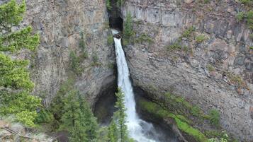 A waterfall cascading down a rocky cliff surrounded by greenery.