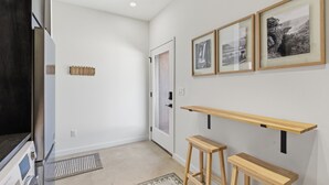 Ein Flur mit Kühlschrank, einer Tür, einem Wandregal und einem Teppich.