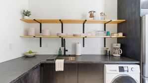 Eine moderne Küche mit integriertem Waschtrockner, Holzregalen und einer Arbeitsplatte.