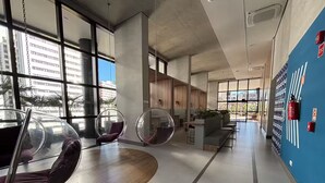 Et moderne interiør med store vinduer, en blå accentvæg og et siddeområde med runde stole.