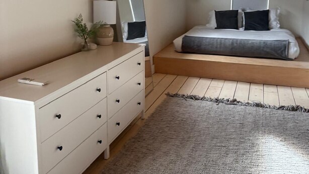 A bedroom with a bed, a dresser, a mirror, and a window.