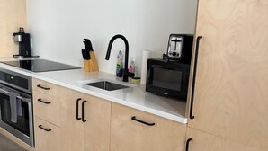 A kitchen with a built-in oven, a microwave, a coffee maker, a sink, and a knife block.